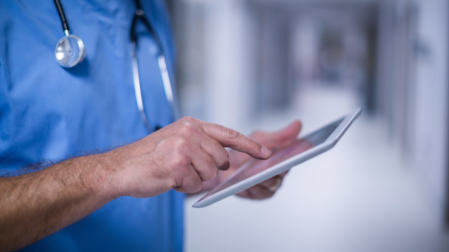 Mid section of male surgeon using digital tablet in operation room at hospital
